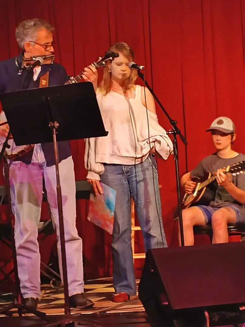 Three musicians performing on stage with instruments.